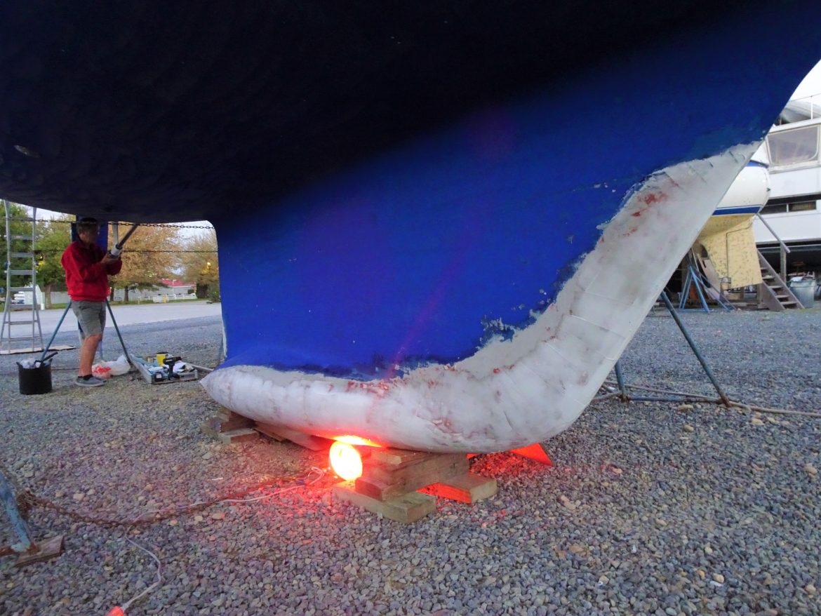 Heating lamp under the keel to cure the epoxy, and Glen works on the propeller way into the night Heating lamp under the keel to cure the epoxy, and Glen works on the propeller way into the night